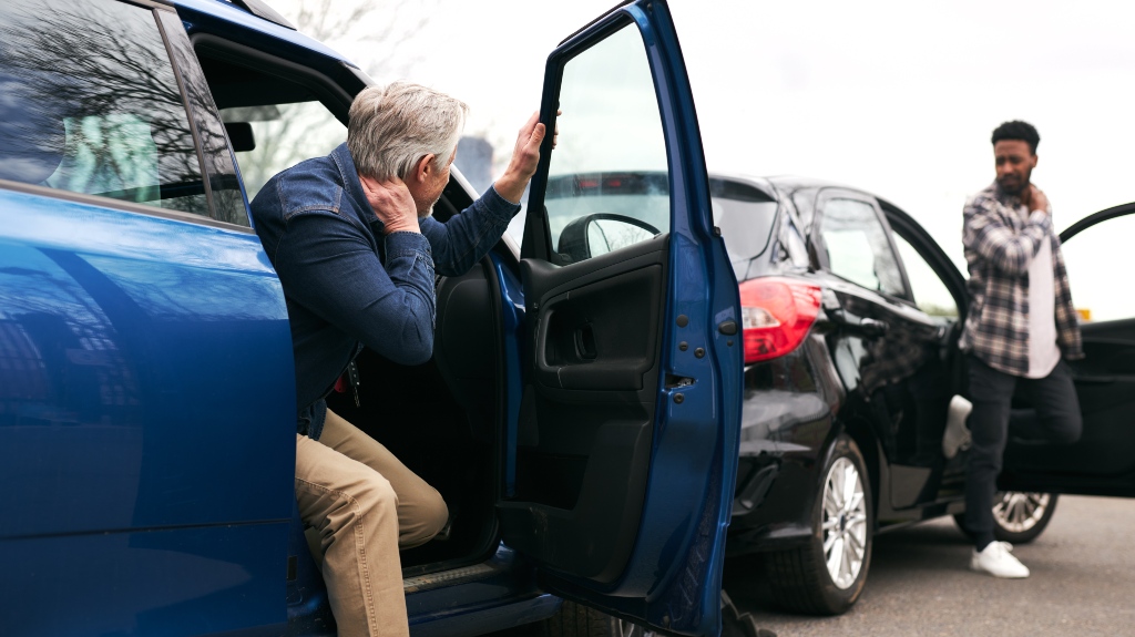 Senior and younger male drivers get out of cars and inspect damage