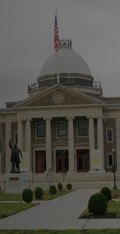 A large building featuring a flag prominently displayed at its peak against a clear sky backdrop.