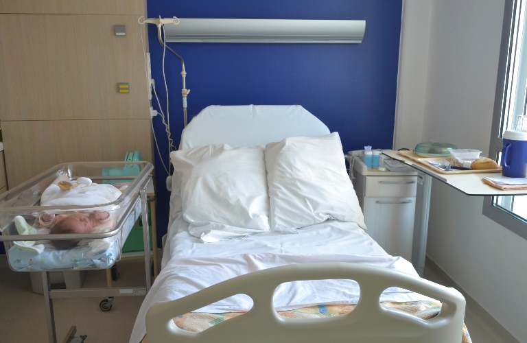 Empty hospital bed for patient and newborn baby near the bed