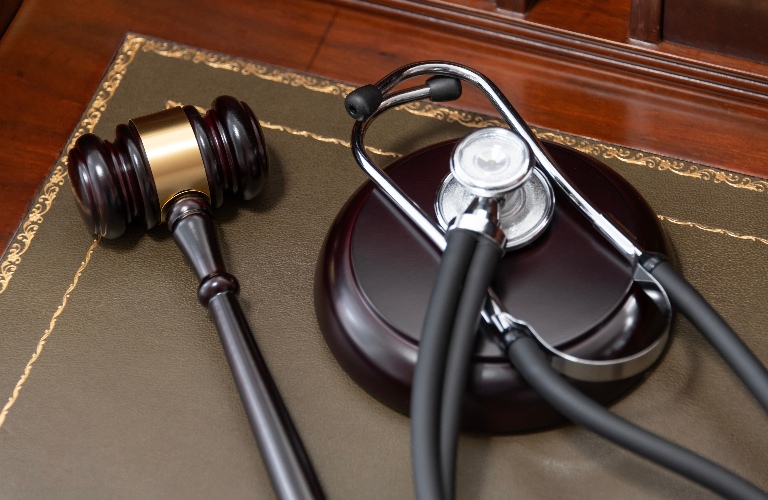 judge's gavel and a black stethoscope on top of a legal book