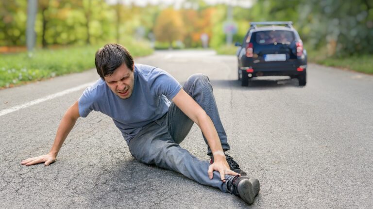Injured man on road in front of a car