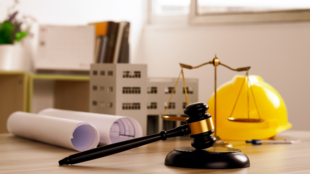 Judge gavel, building blueprint plans with a yellow safety helmet